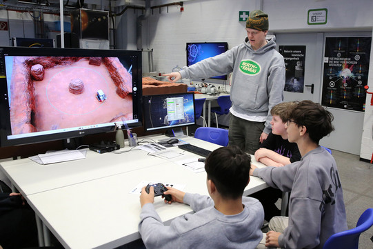 Schüler mit ferngesteuertem Fahrzeug in simulierter Mars-Umgebung